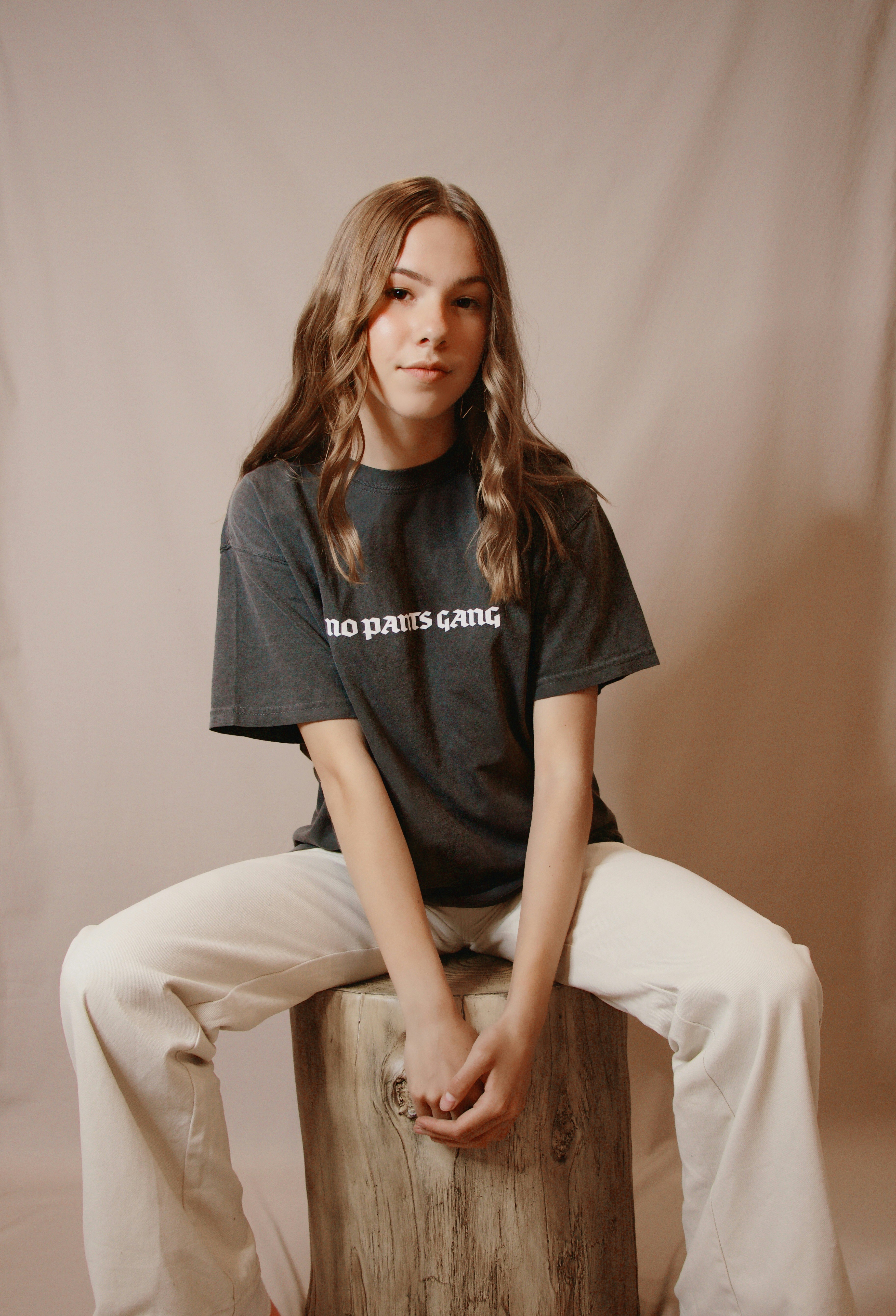 woman in black crew neck t-shirt and white pants sitting on brown wooden seat
